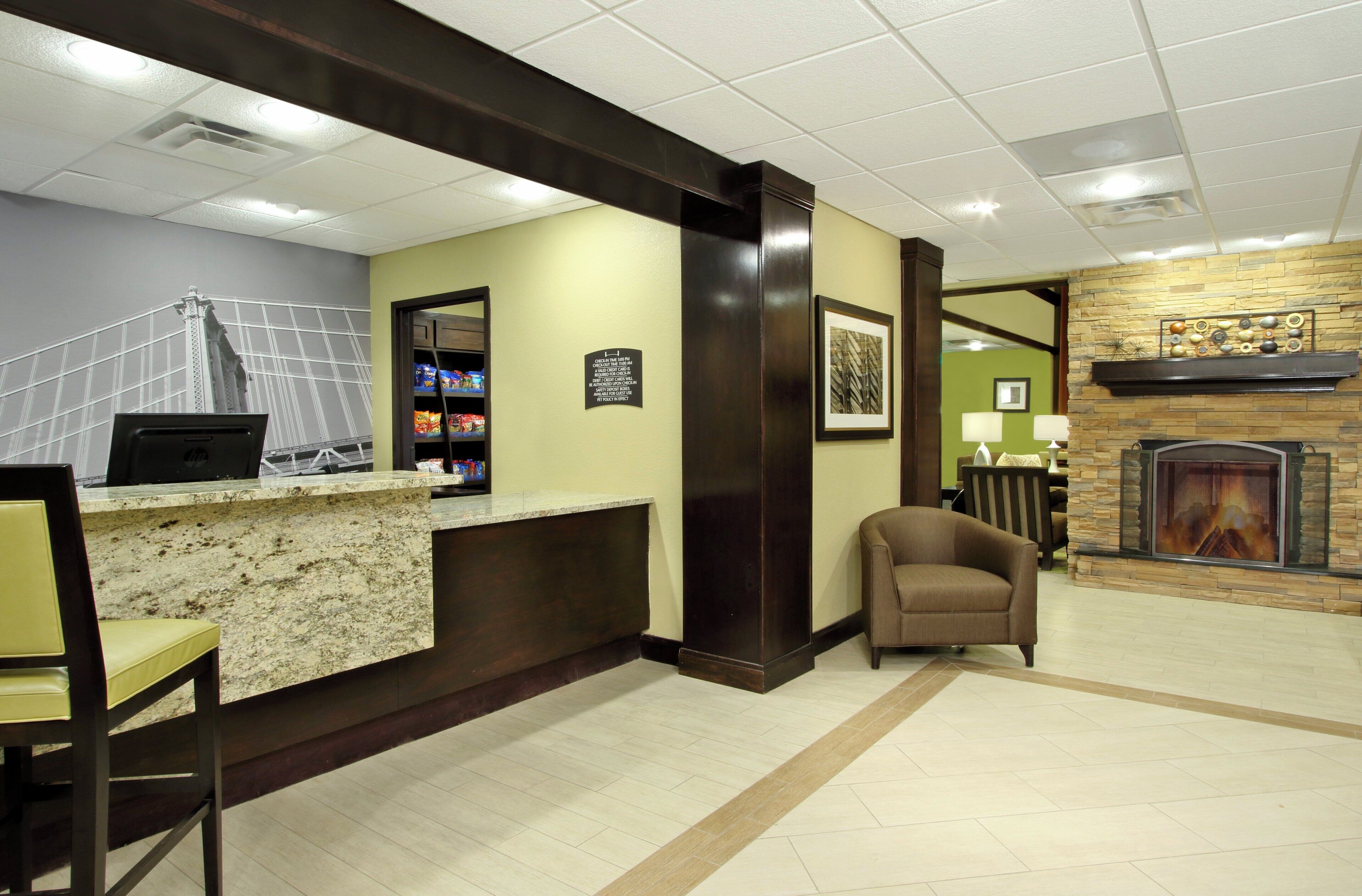 A hotel lobby with a reception desk, a seating area, a fireplace, and a wall with a decorative piece.