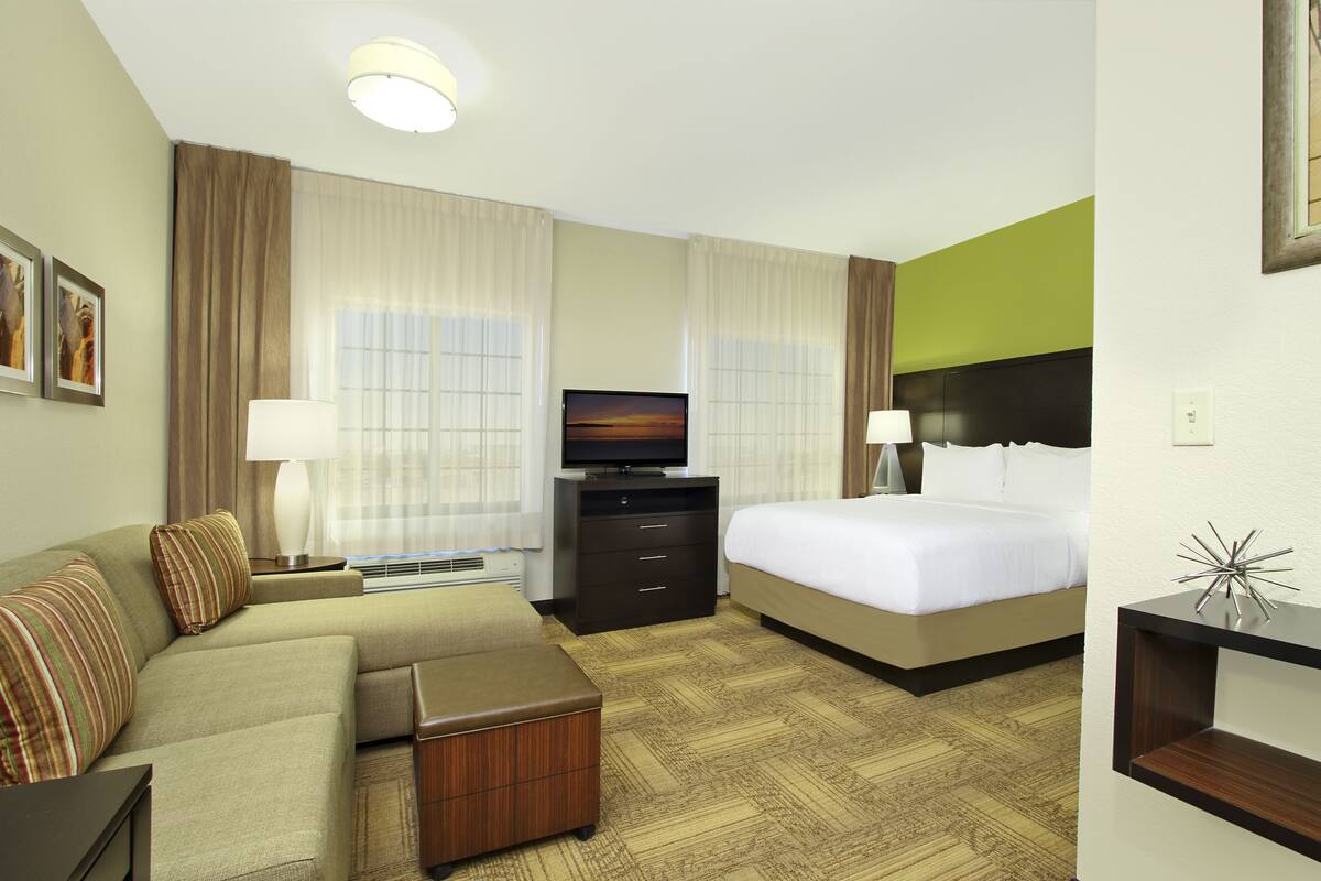 Ein Hotelzimmer mit Bett, einer Couch, einem Fernseher und einem Schreibtisch.