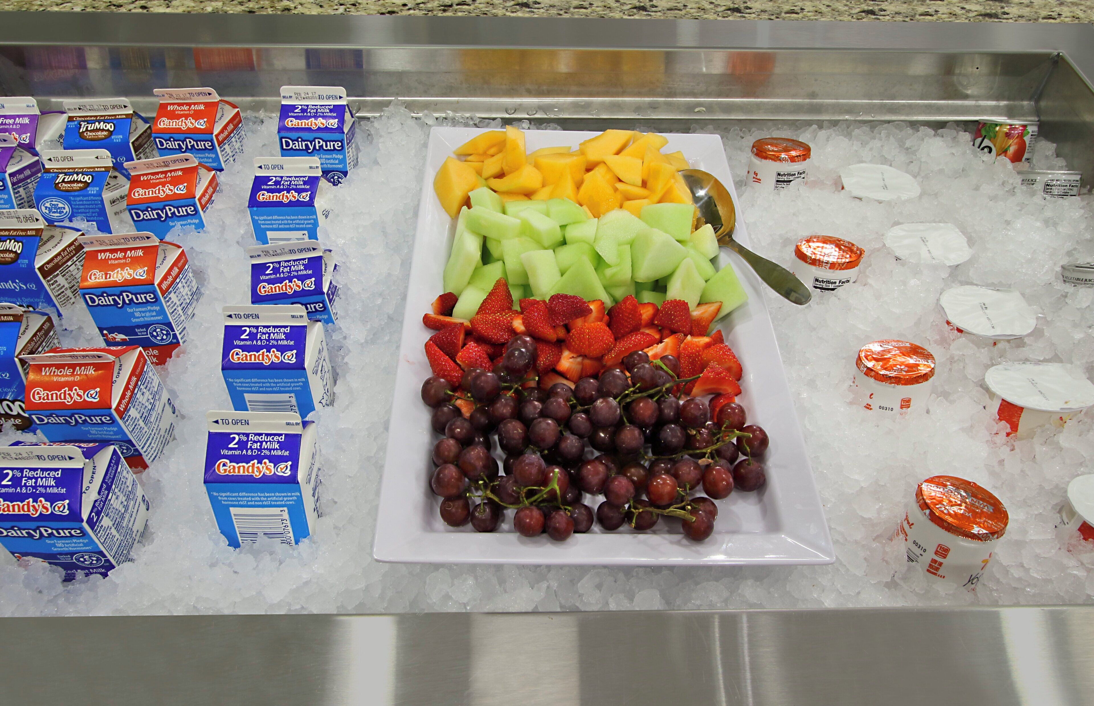 Un buffet proposant une variété de produits laitiers, de fruits et un assortiment de jus de fruits.