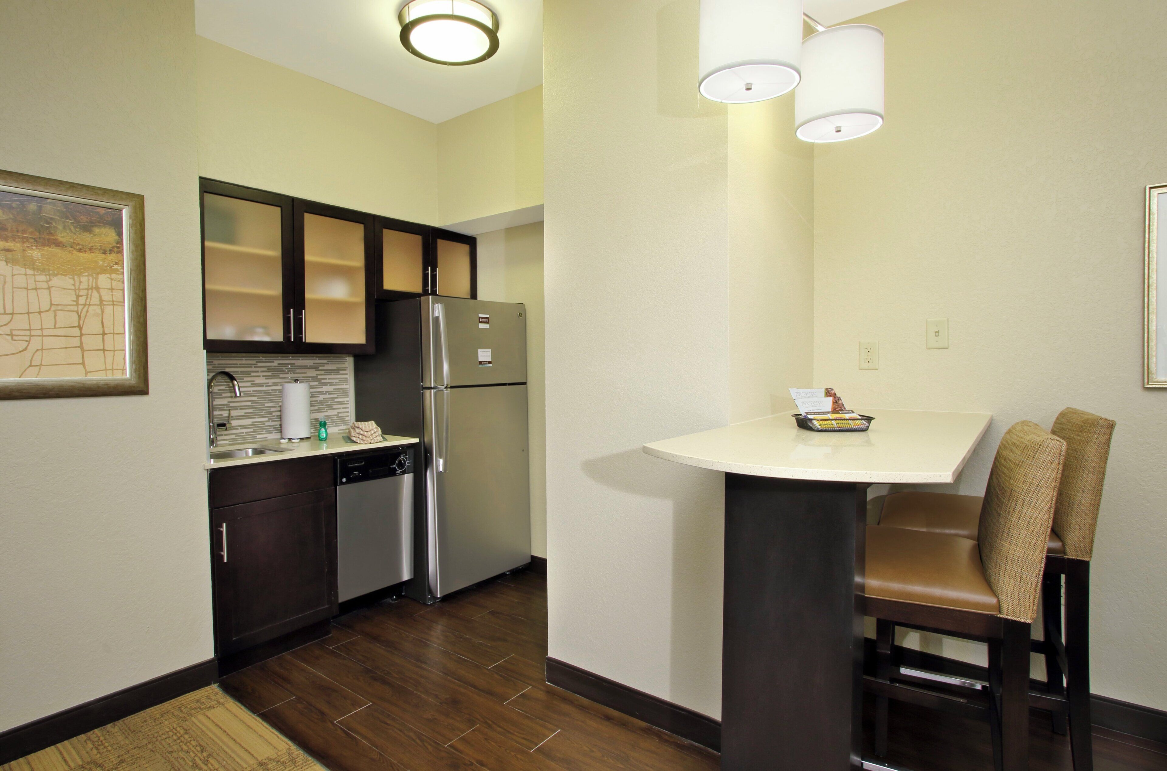 A compact kitchen with a refrigerator, dishwasher, and a small dining table with two chairs.