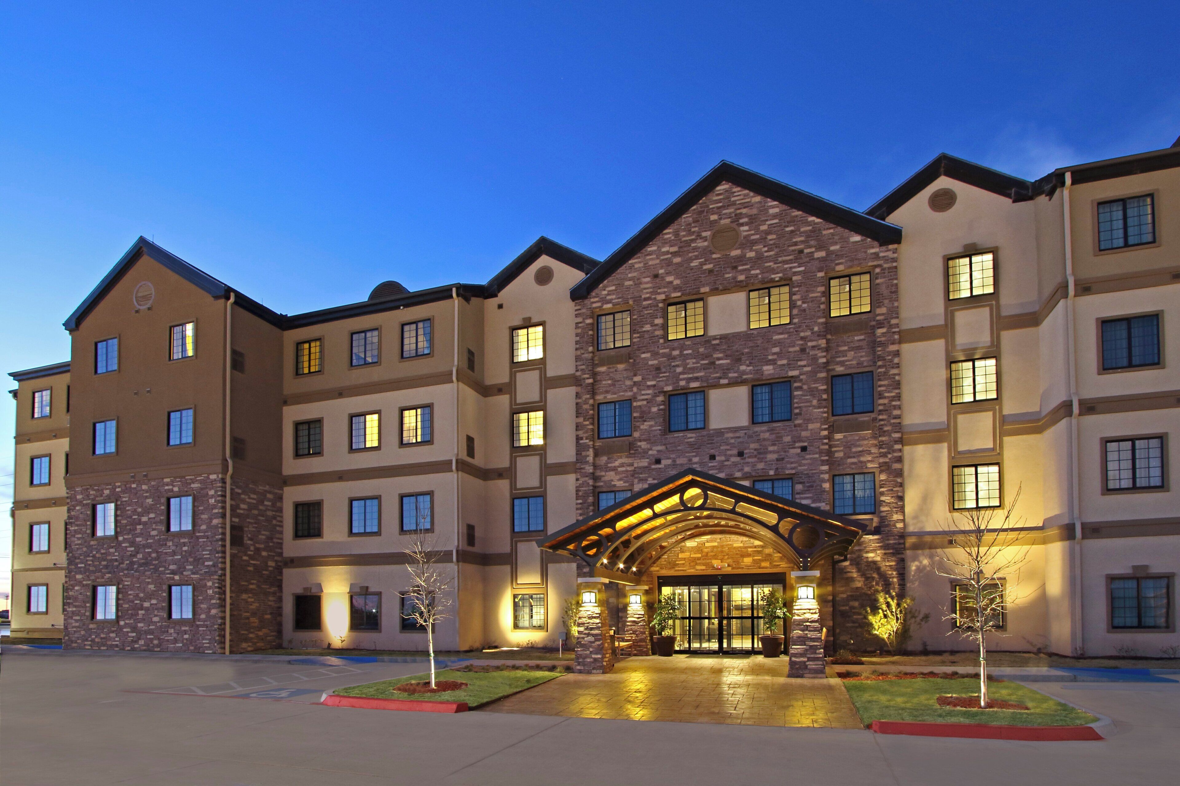 A multi-story hotel with a central entrance featuring a stone facade and a covered walkway.