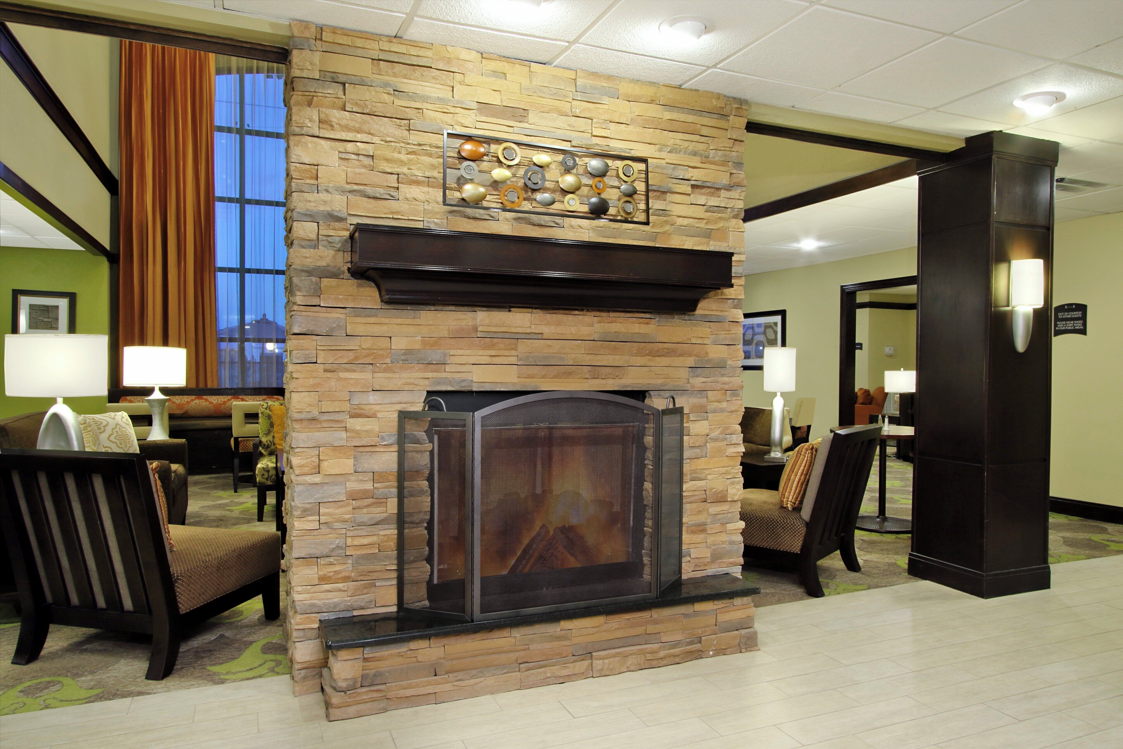 A hotel lobby with a stone fireplace, seating area, and a view of the outdoors.