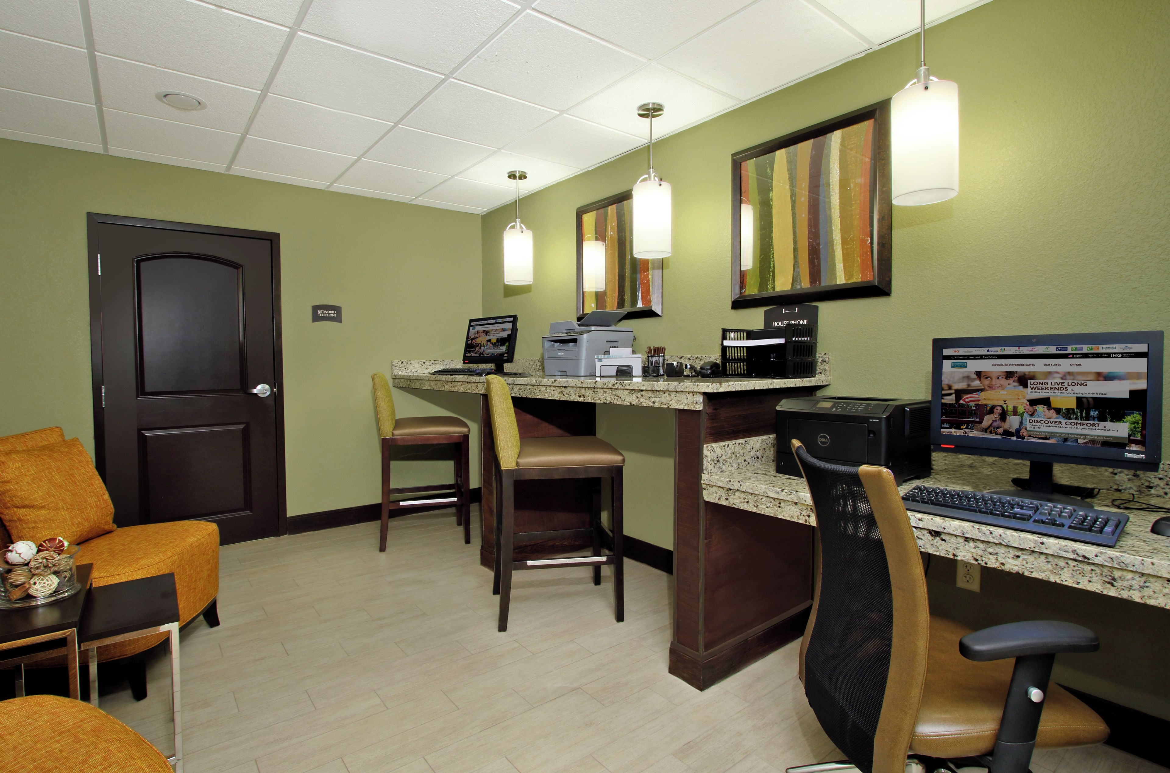 A reception area with a desk, computer, chairs, and a door.