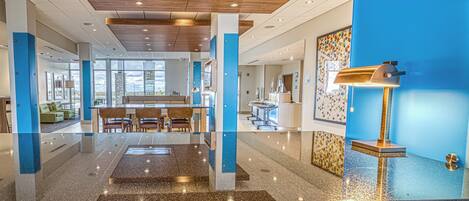A hotel lobby with a reception desk, seating area, and a view of the outside.