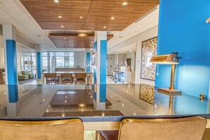 Un hall d’hôtel comprenant un comptoir d’accueil, un espace salon et une vue sur l’extérieur.