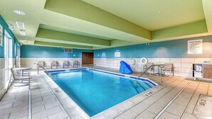 An indoor swimming pool with tiled walls, a wooden door, and a sign indicating pool rules.