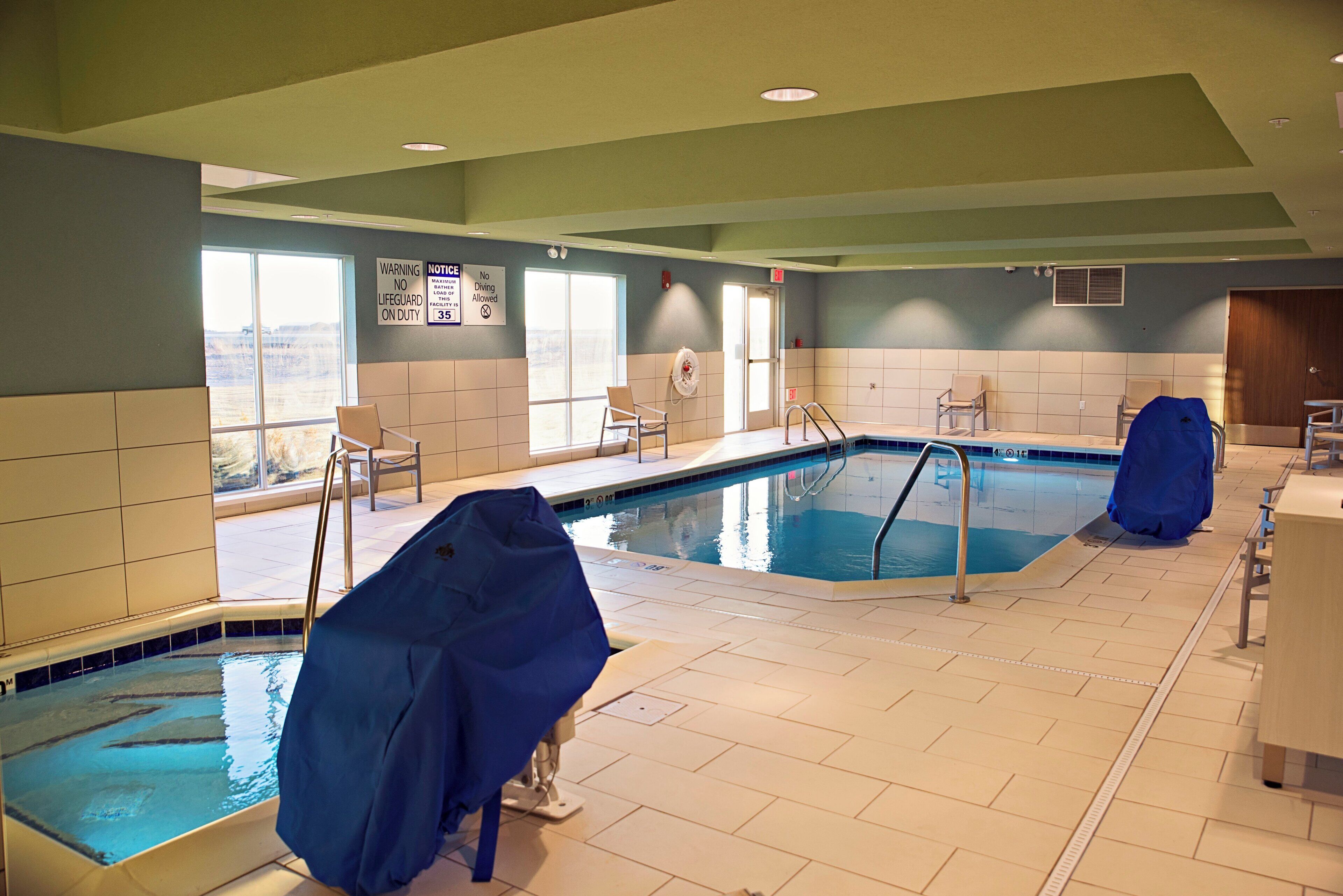 Une piscine intérieure avec deux couloirs de nage, des murs carrelés et un poste de surveillance pour le sauveteur.