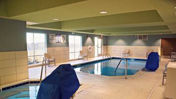 Une piscine intérieure avec deux couloirs de nage, des murs carrelés et un poste de surveillance pour le sauveteur.