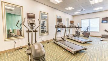 Een fitnessruimte met loopbanden, elliptische trainers en krachttrainingsapparatuur.