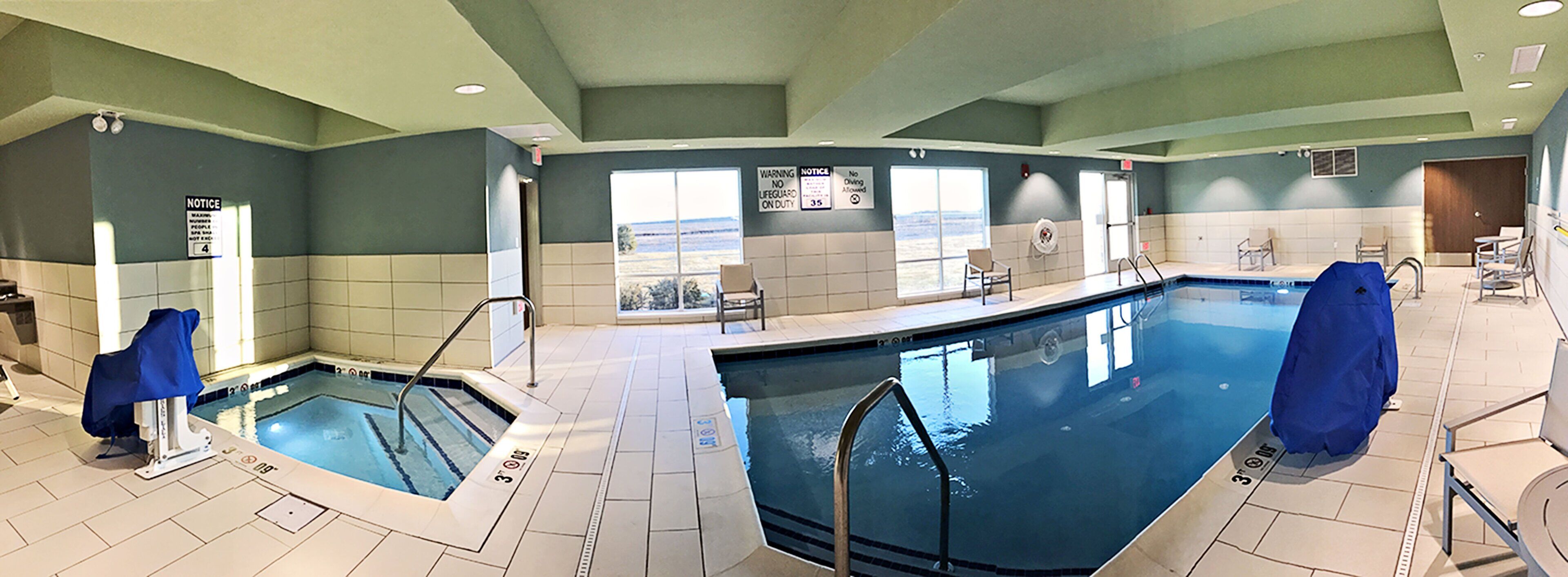 A large indoor swimming pool with clear water, multiple lanes, and safety signage.
