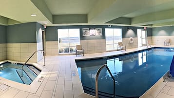 A large indoor swimming pool with clear water, multiple lanes, and safety signage.