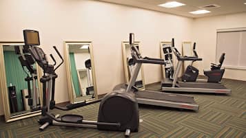 A fitness room with multiple exercise machines, including treadmills and elliptical trainers, and a water dispenser.
