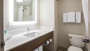 Un baño con lavamanos blanco, un espejo, un inodoro y un perchero para toallas.