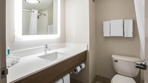 Une salle de bain avec un lavabo blanc, un miroir, des toilettes et un porte-serviettes.