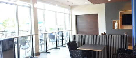A modern interior with a seating area, large windows, and a flat-screen TV on the wall.