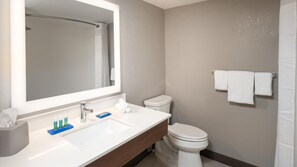 Une salle de bain moderne avec un grand miroir, un lavabo blanc, des toilettes et un porte-serviettes.
