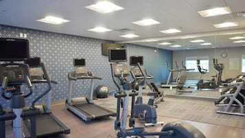 Een sportschool met loopbanden, elliptische trainers en gewichten.
