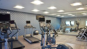 Un gimnasio con cintas de correr, elípticas y equipo de pesas.