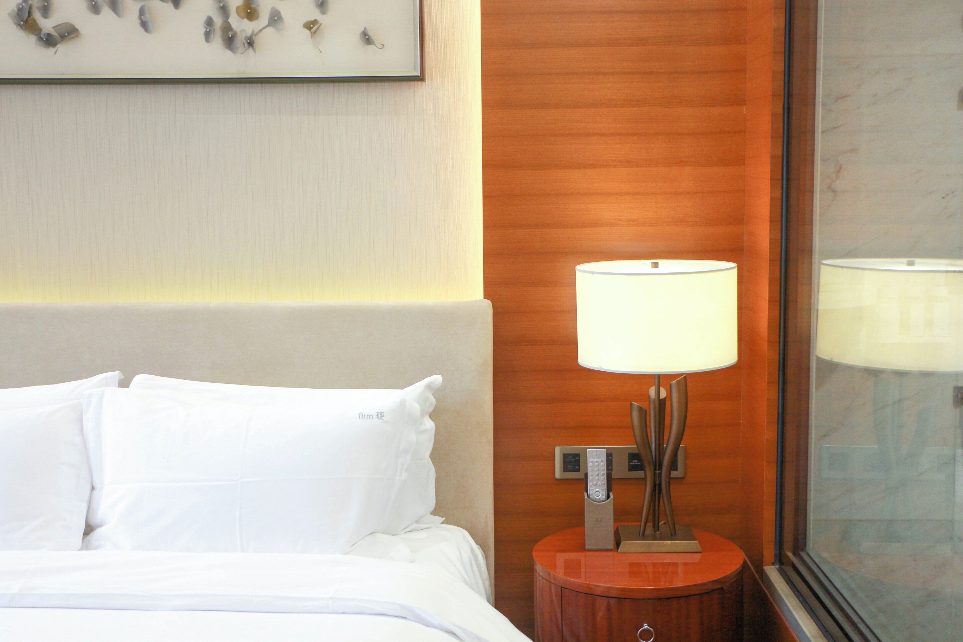 Ein Hotelzimmer mit einem Bett, einem Nachttisch mit Lampe und einem Wandbild.