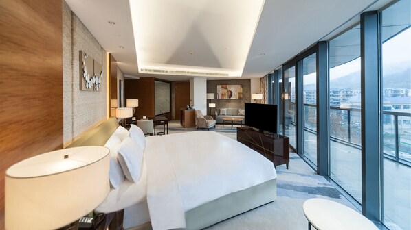 Habitación de hotel moderna con una cama grande, televisión, escritorio y vistas a la ciudad.