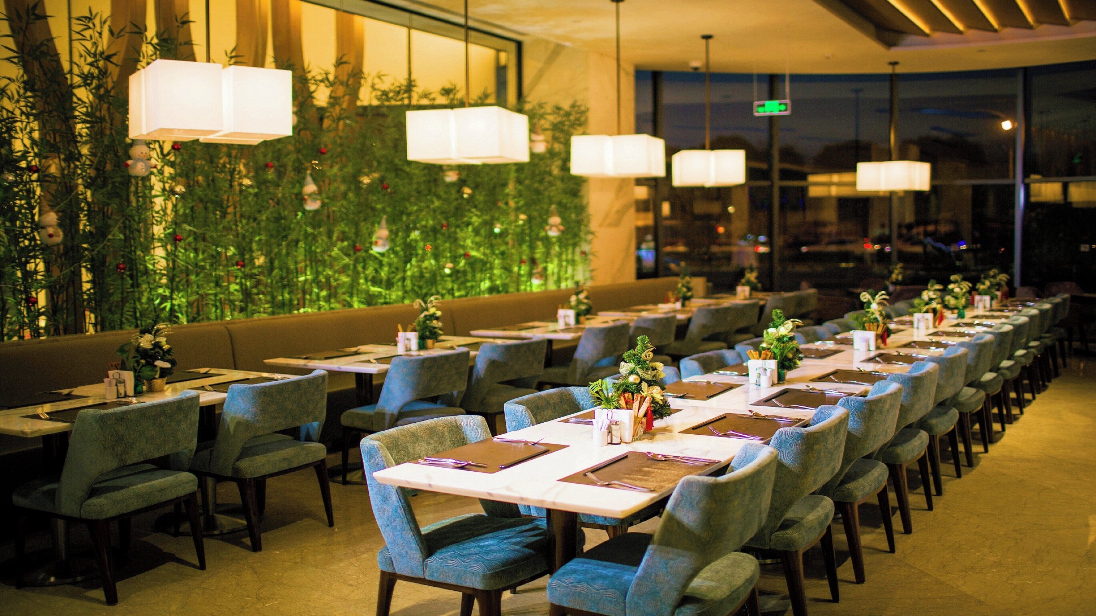 Ein Restaurant mit langen Tischen, Stühlen und hängenden Lampen.