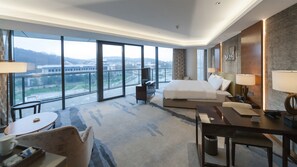 A hotel room with a large bed, a desk, a chair, a TV, and a view of a cityscape through large windows. - Holiday Inn Nanjing Xuanwu Lake by IHG (Nanjing)