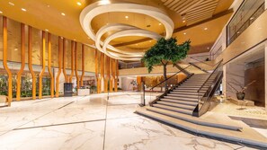 A spacious lobby with a marble floor, a staircase, and a large tree. - Holiday Inn Nanjing Xuanwu Lake by IHG (Nanjing)