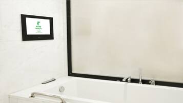 A bathroom with a bathtub, a framed sign on the wall, and a window.