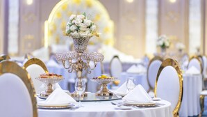 A banquet table set with fine china, silverware, and a centerpiece of white flowers.