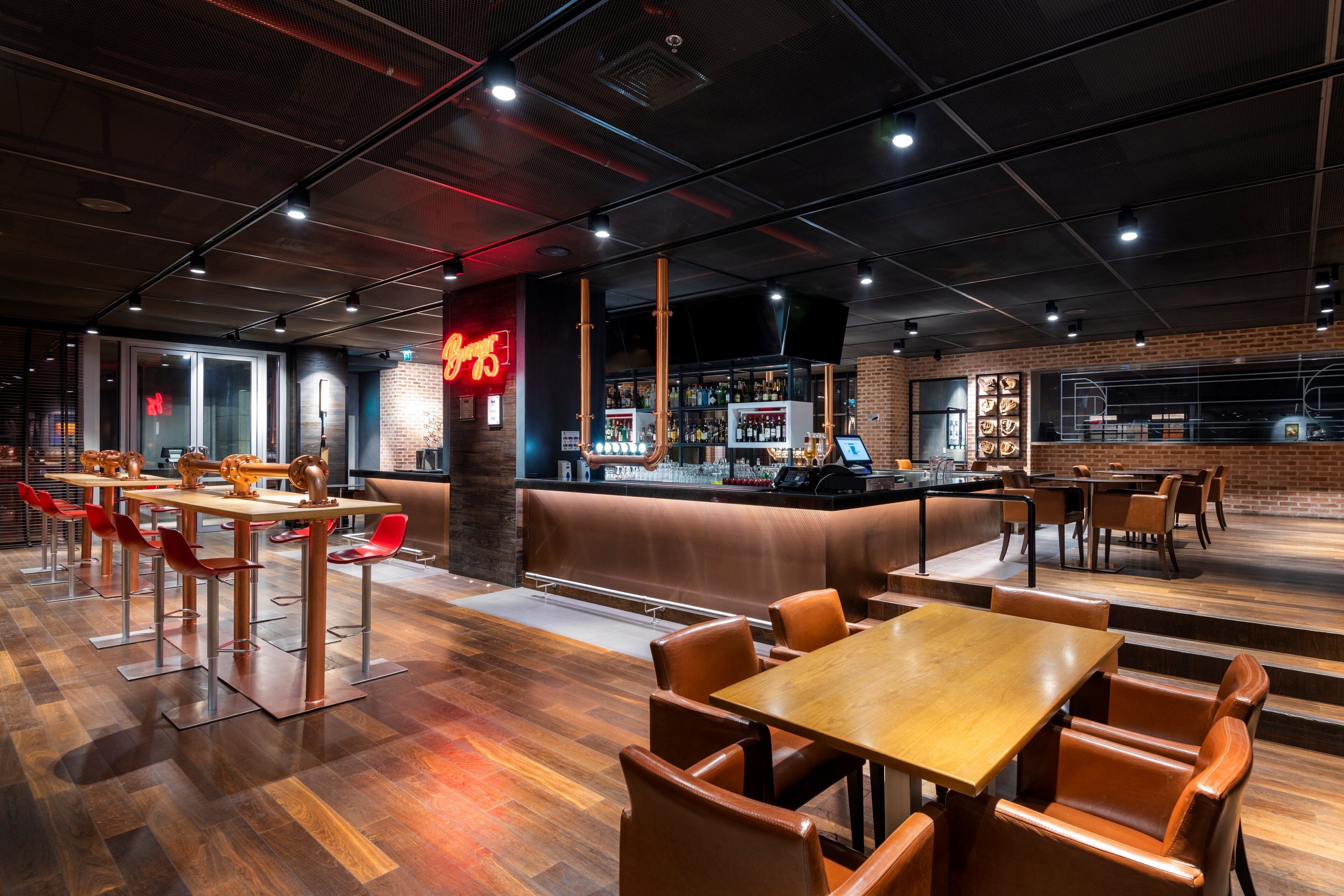 A modern bar area with a counter, seating, and a neon sign.
