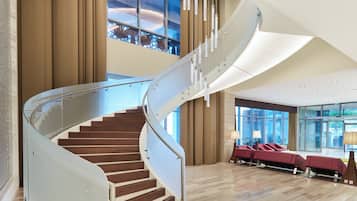 A modern hotel lobby with a spiral staircase, seating area, and large windows.
