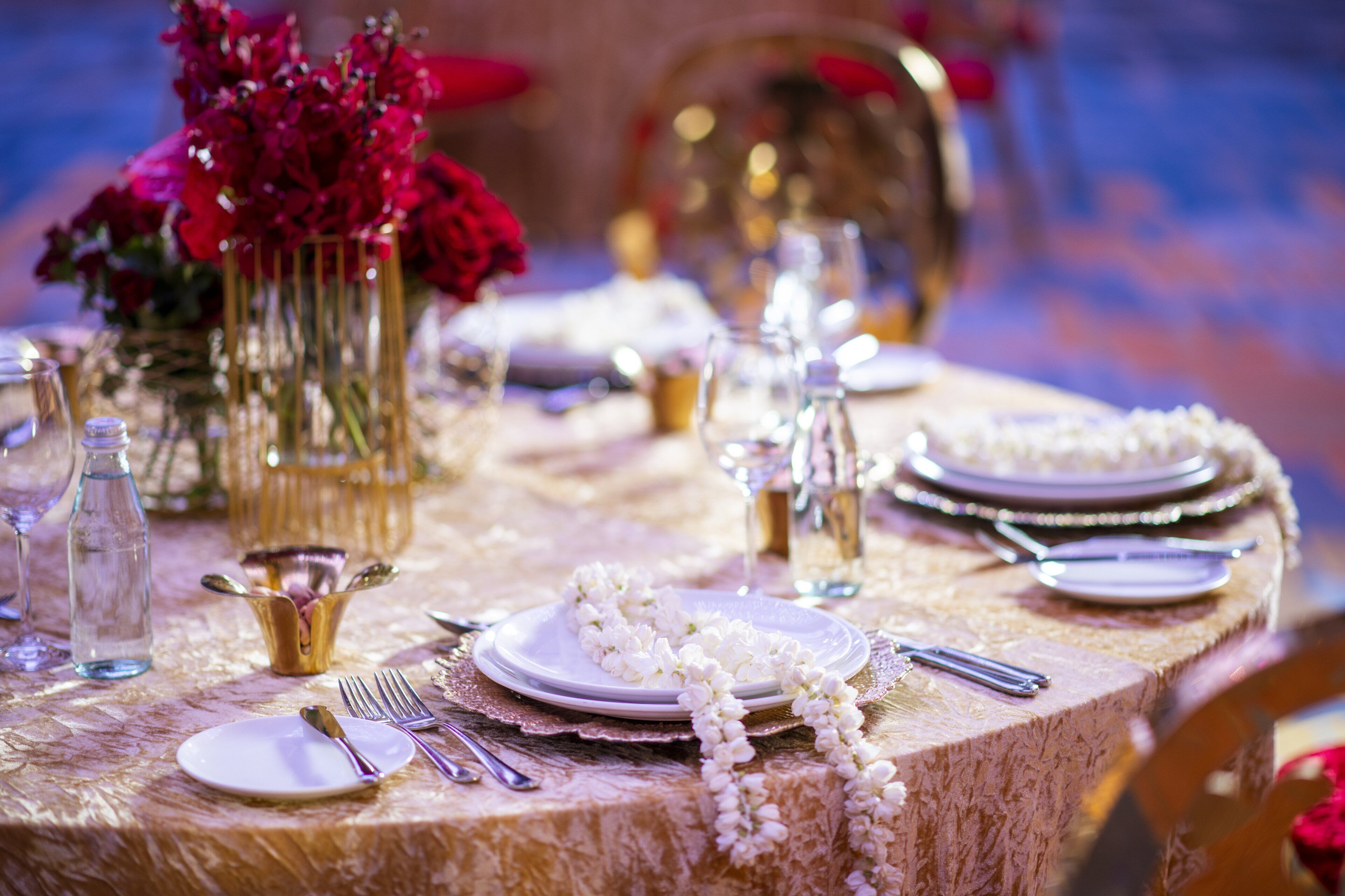 A table set with white plates, silverware, and a garland of white flowers.