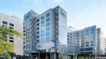 Ein mehrstöckiges Holiday Inn Hotel mit modernem Design, das eine markante Einfahrt und eine große Glasfassade aufweist.
