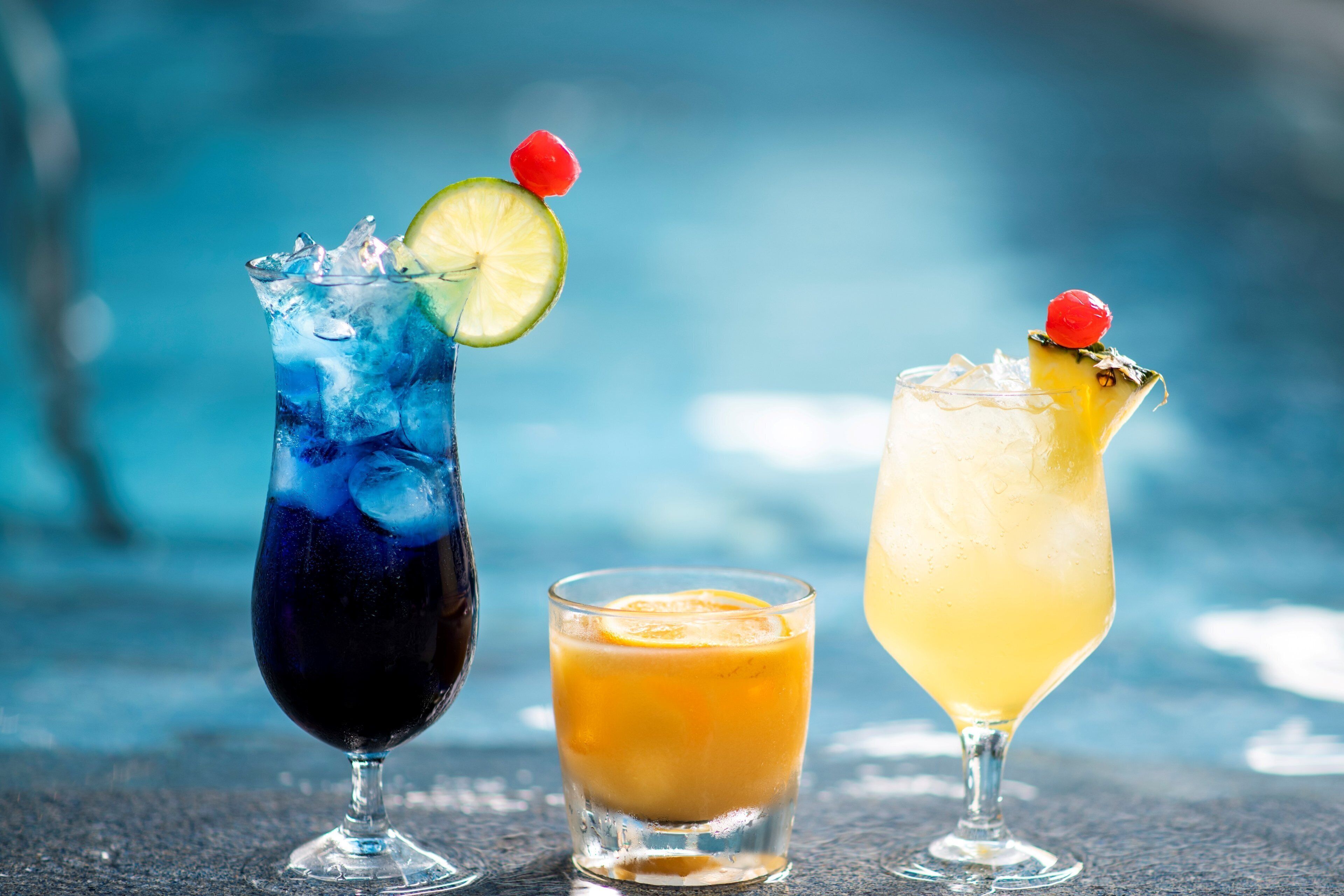 Three different drinks in glasses, each with a unique garnish.