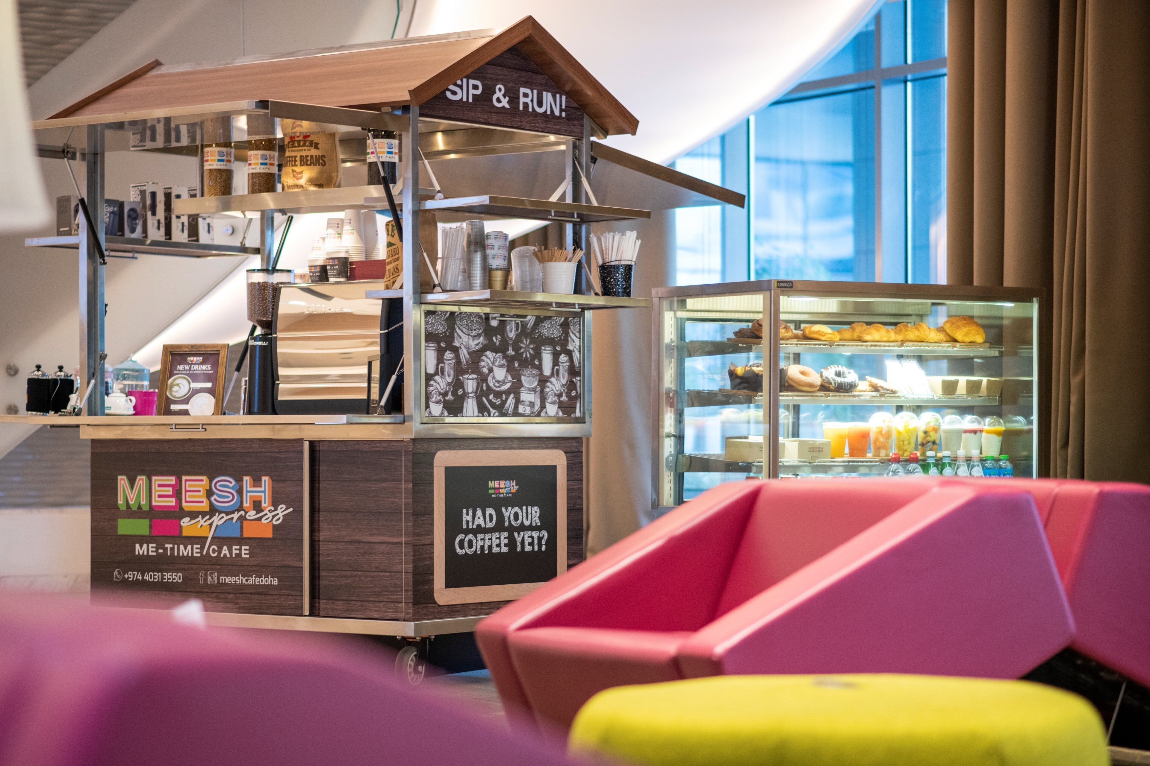 Un quiosco de café con un letrero que dice 'MEESH ME-TIME CAFE' y la pregunta '¿YA TOMÓ SU CAFÉ?' con un número de contacto.