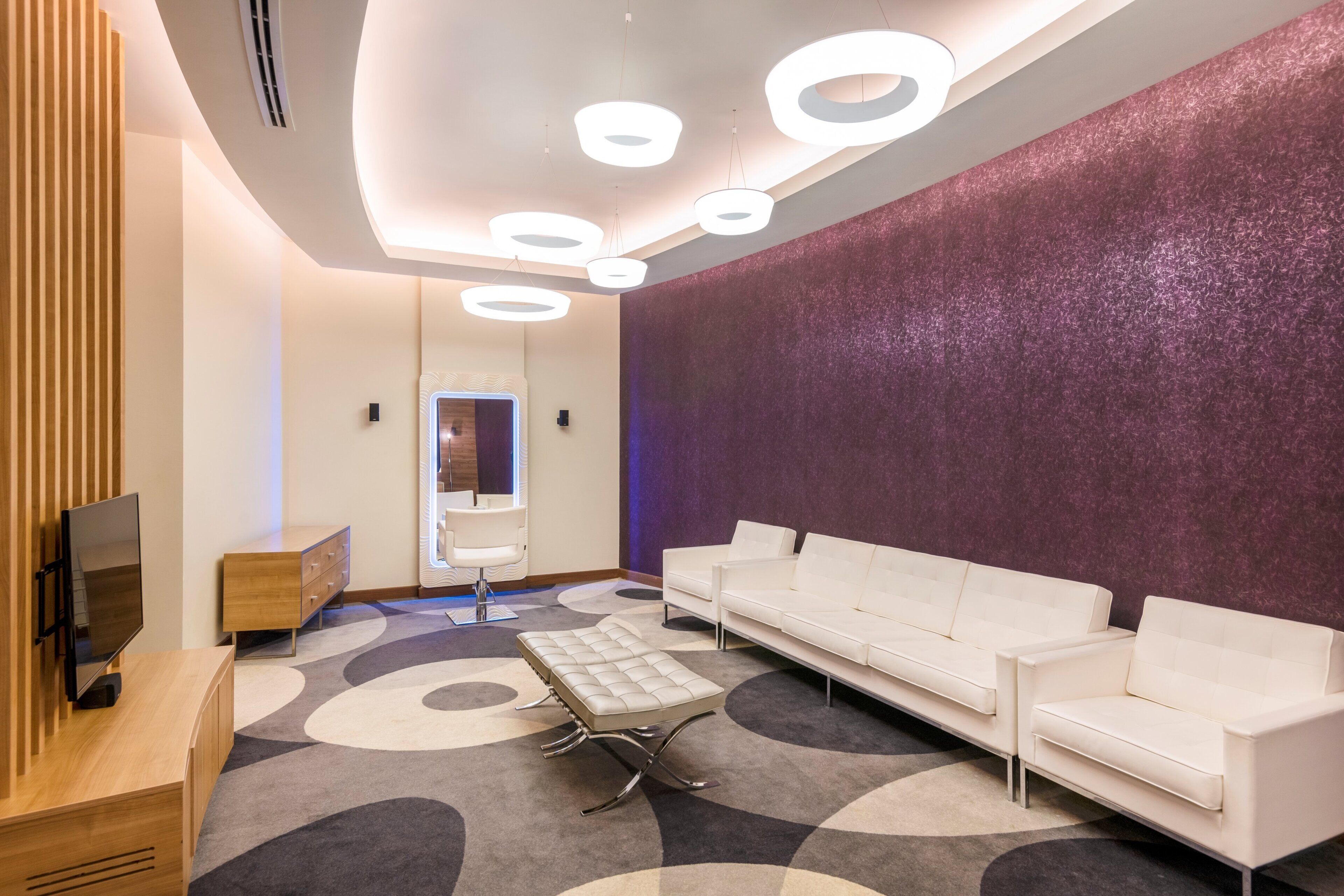 A modern waiting area with a sofa, a television, and a patterned carpet.