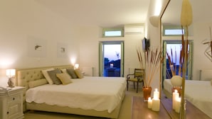 Un dormitorio con una cama grande, mesitas de noche, un espejo y velas.