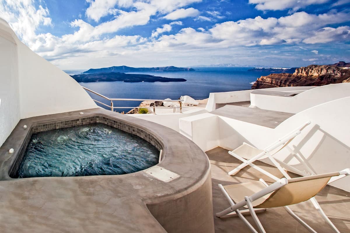 A hot tub with a view of the sea and a mountainous landscape.