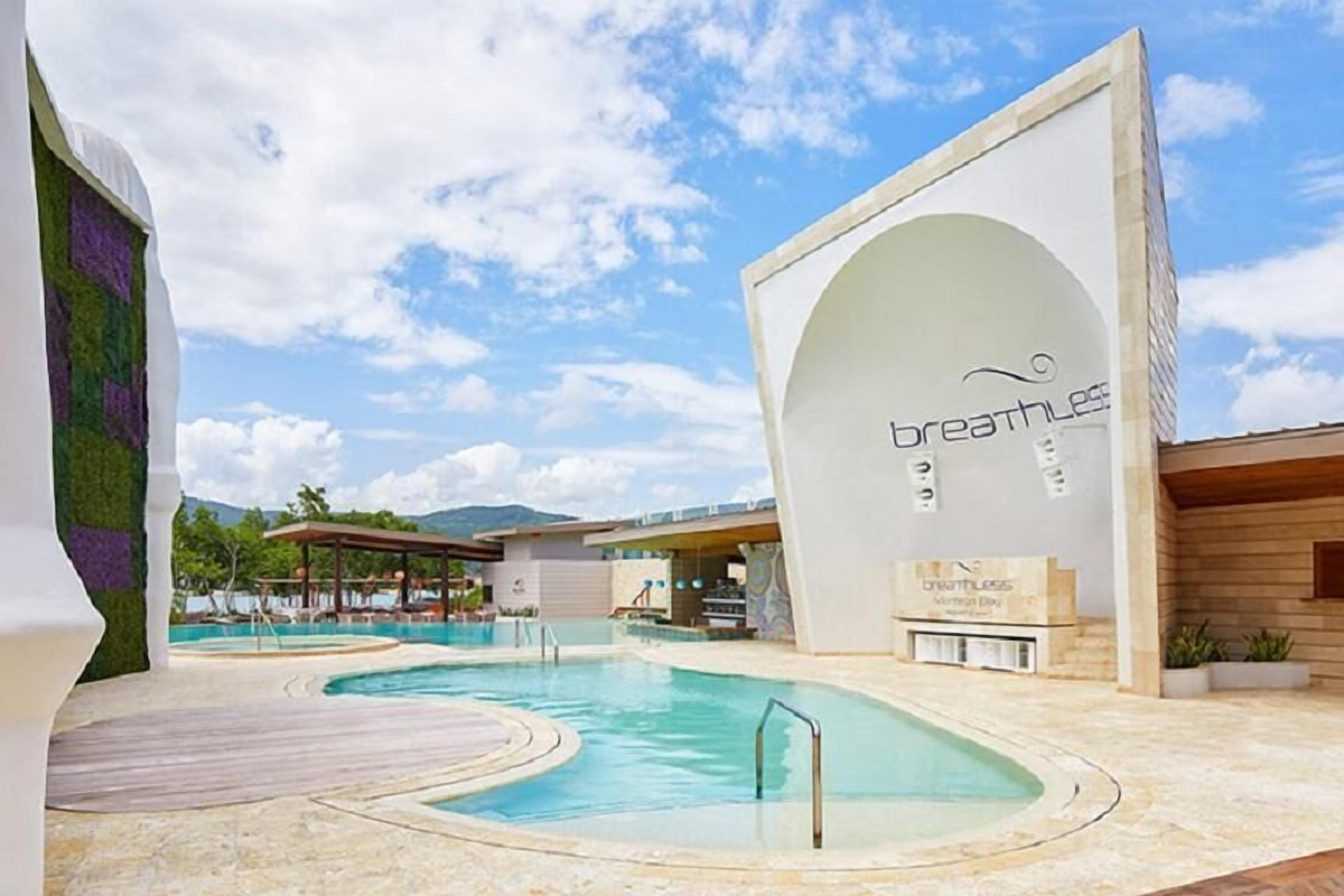 A pool area with a sign reading "breathless" and a view of mountains in the background.