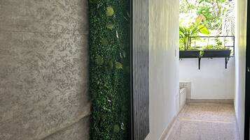 Een gang met een structuurwand, een verticale tuin en een raam met planten.