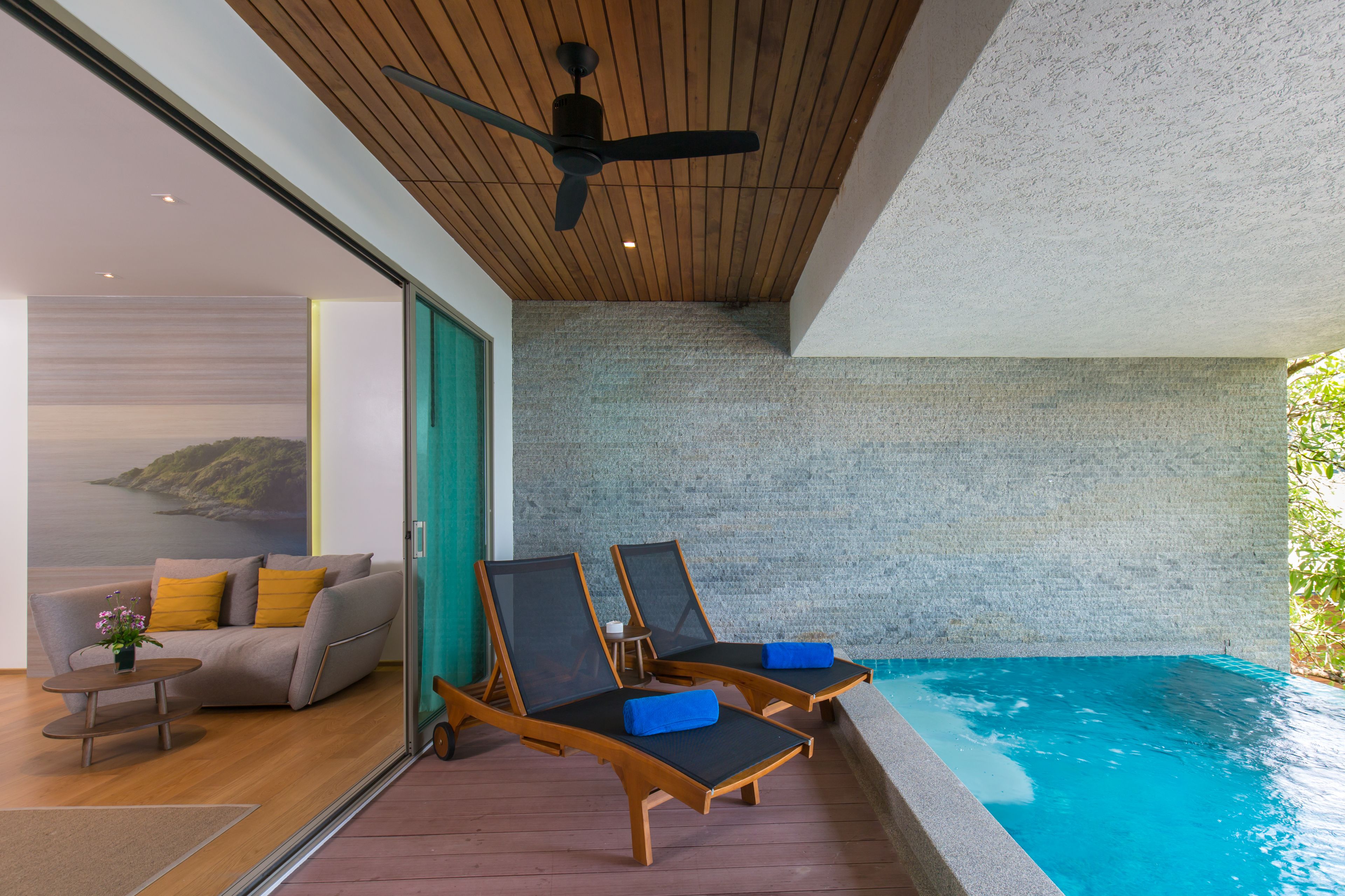 A modern room with a wooden ceiling, a pool, and a sofa with cushions.