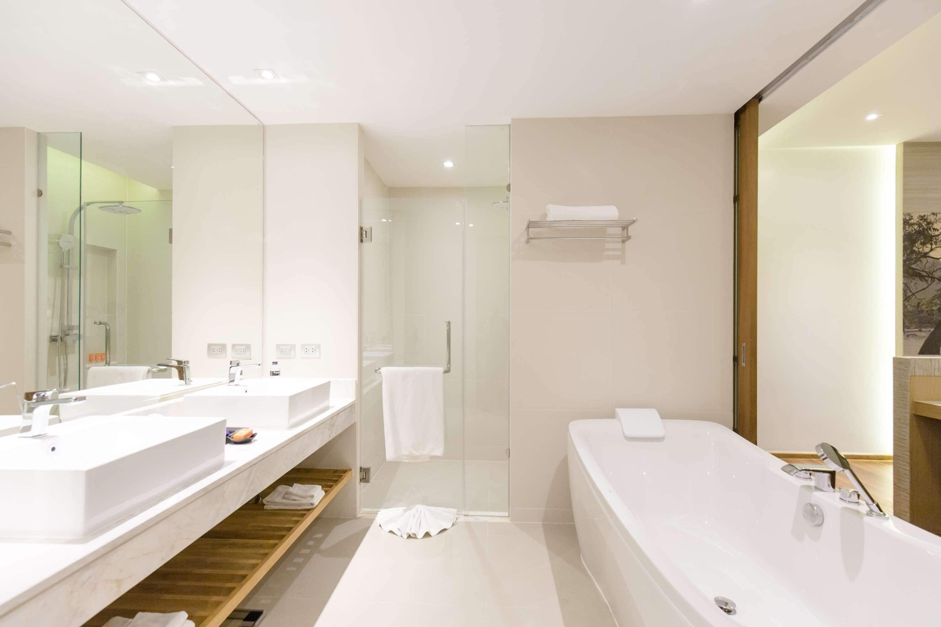 A modern bathroom with two sinks, a shower, and a bathtub.