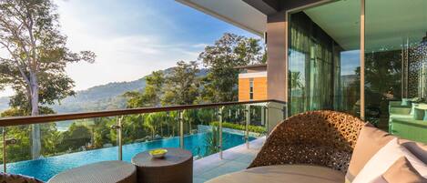 Un balcon donnant sur une piscine, avec des meubles en osier et une balustrade en verre.