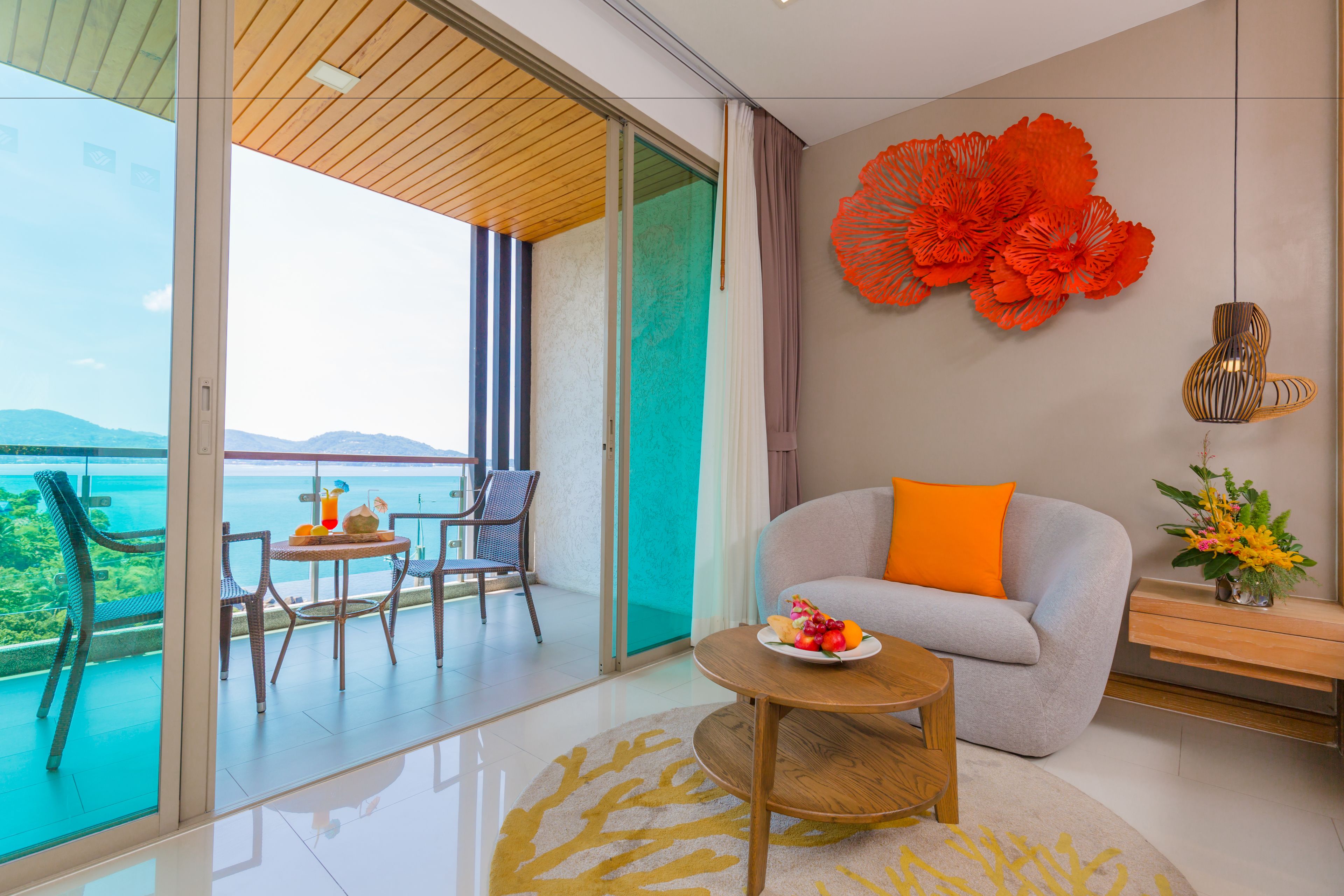 A modern living room with a sofa, a coffee table, and a balcony with a view of the sea.
