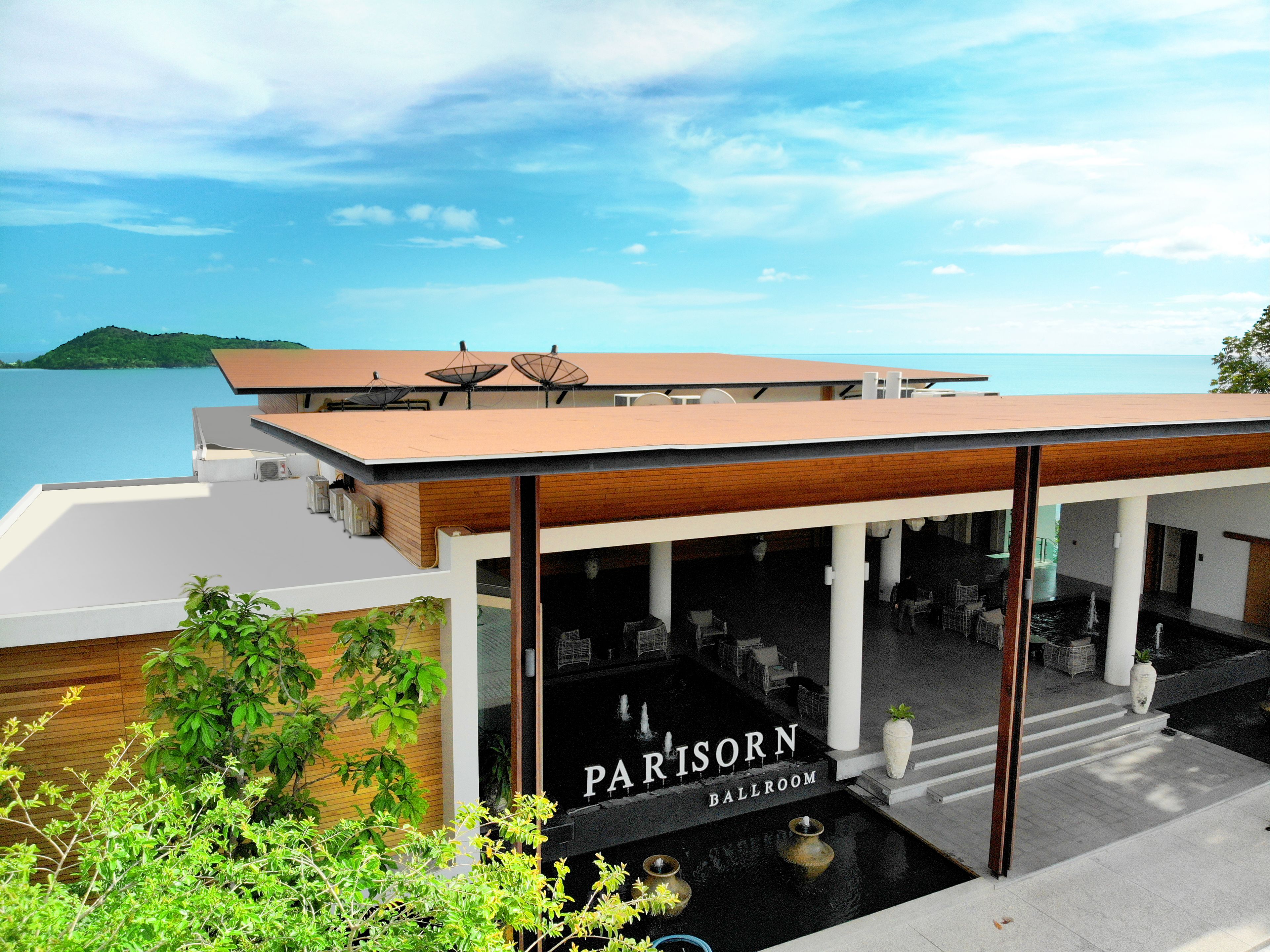 A modern building with a sign reading "PARISORN BALLROOM" and a view of the sea.