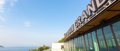 A modern hotel with a large glass facade and a view of the sea.