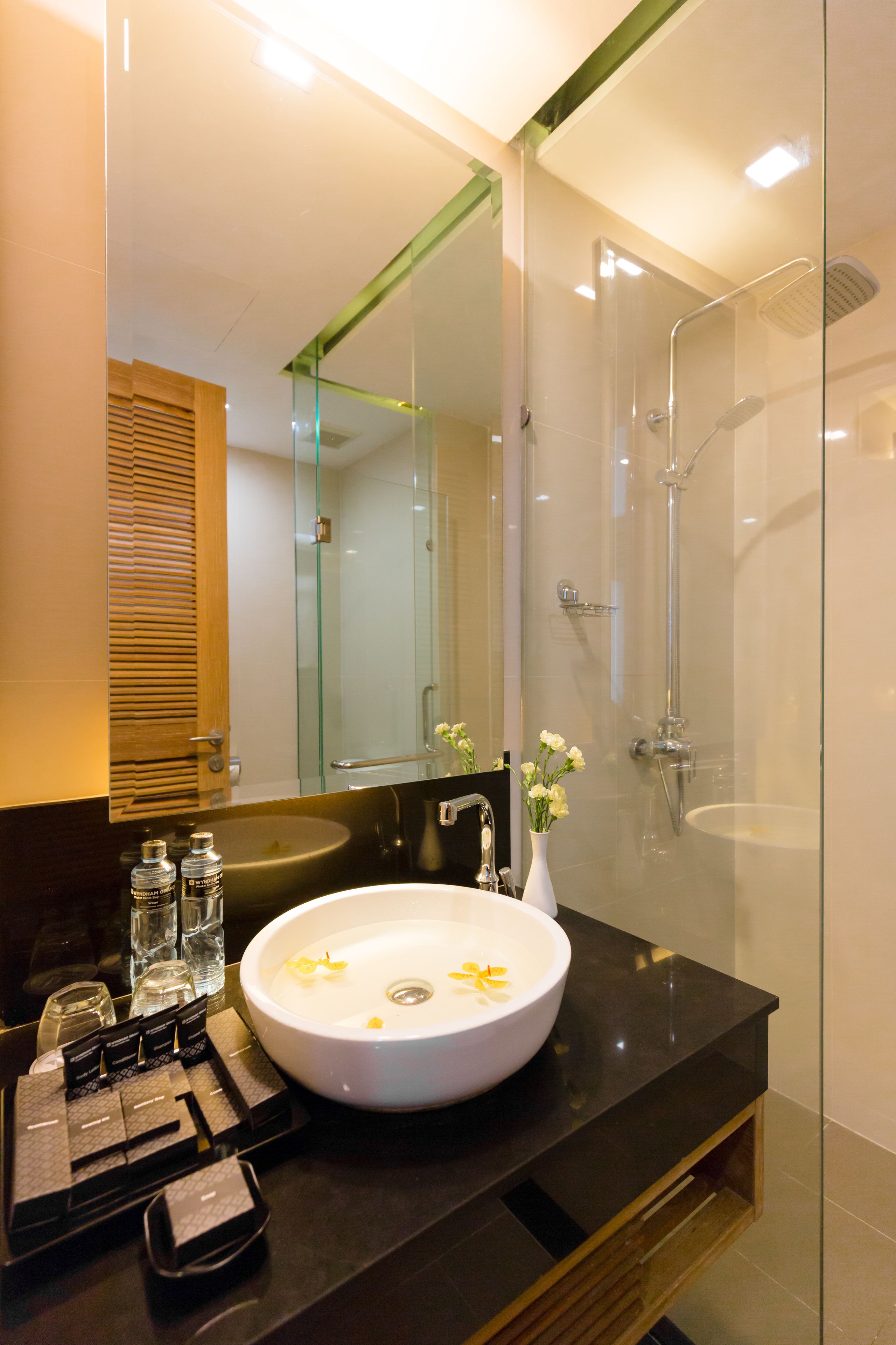 A modern bathroom with a large mirror, a white sink, and a glass-enclosed shower.