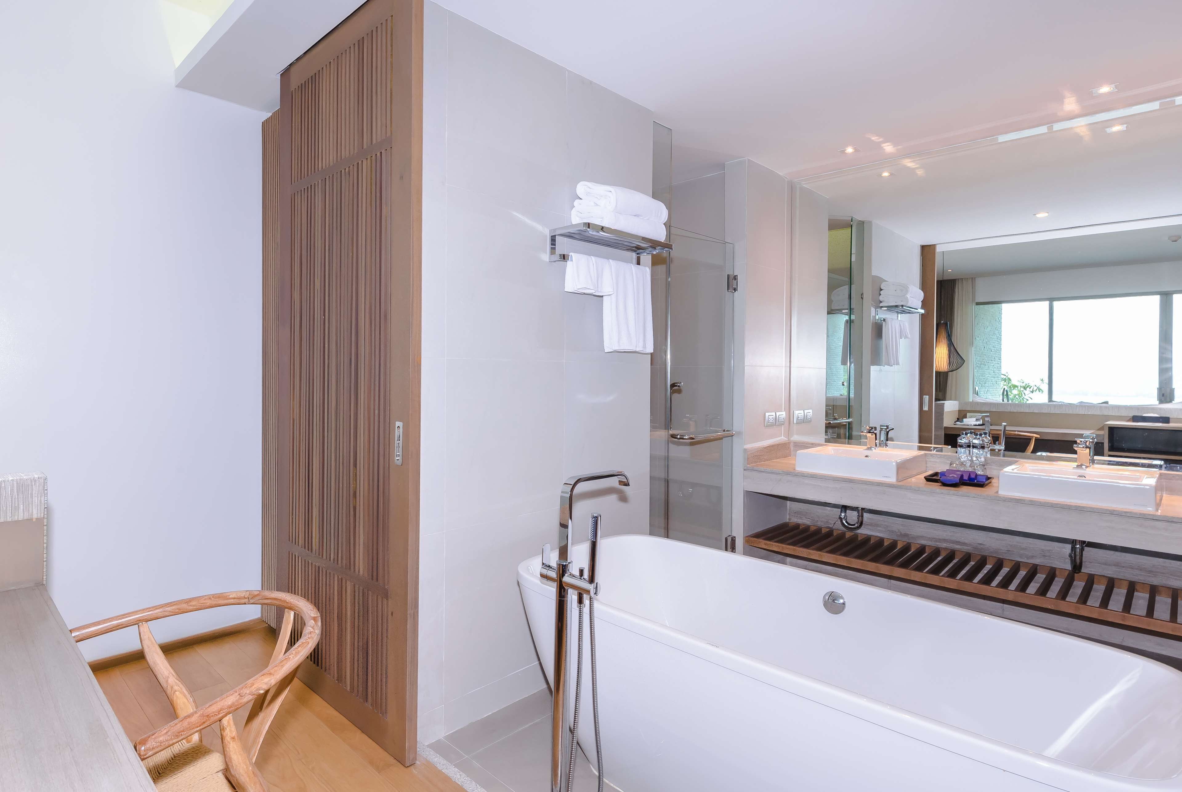 Un baño moderno con una bañera grande, dos lavamanos y una puerta de madera.