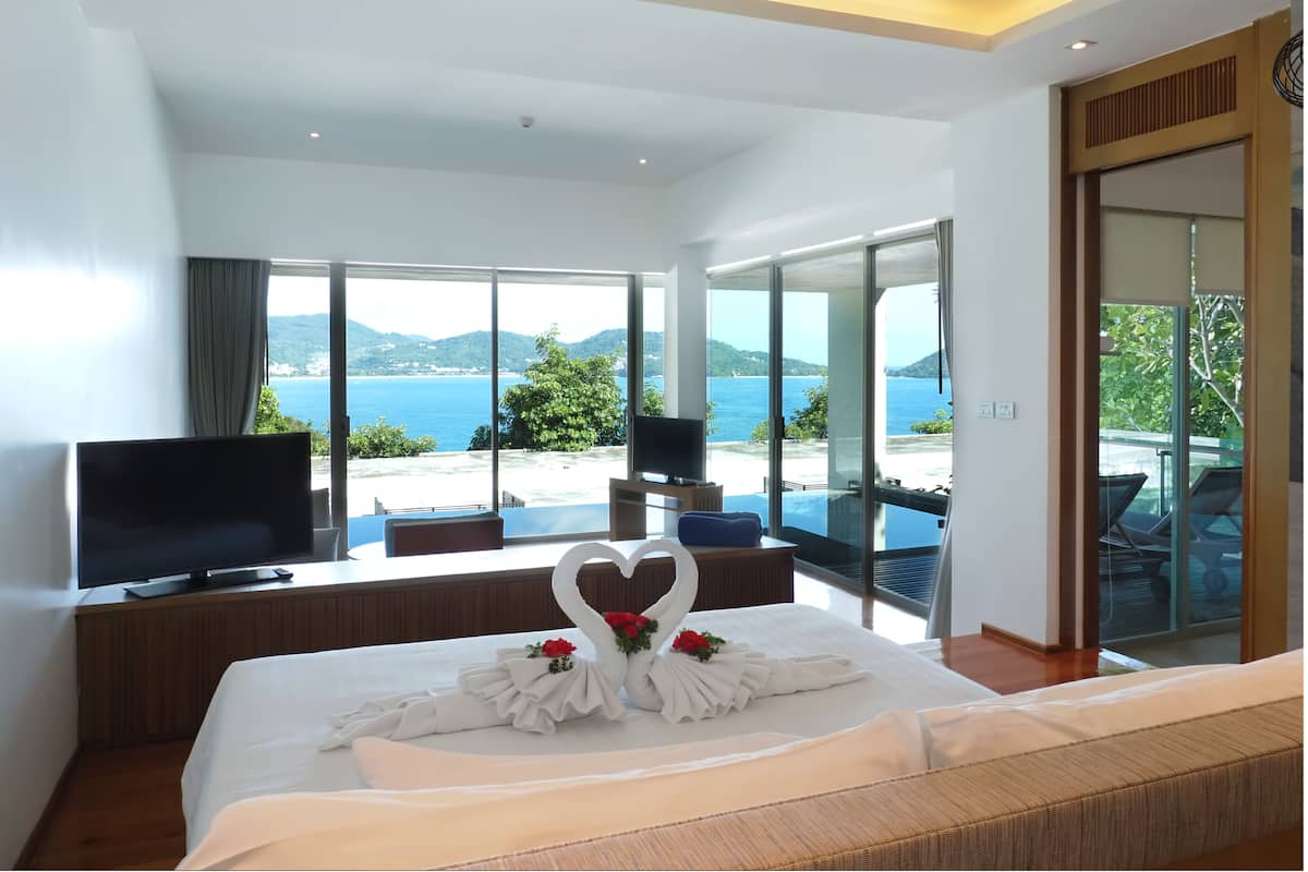 Une chambre d’hôtel moderne dotée d’un grand lit, d’un téléviseur à écran plat et offrant une vue magnifique sur l’océan.