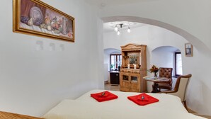 Una habitación de hotel con una cama, un armario de madera, una silla y un cuadro en la pared.